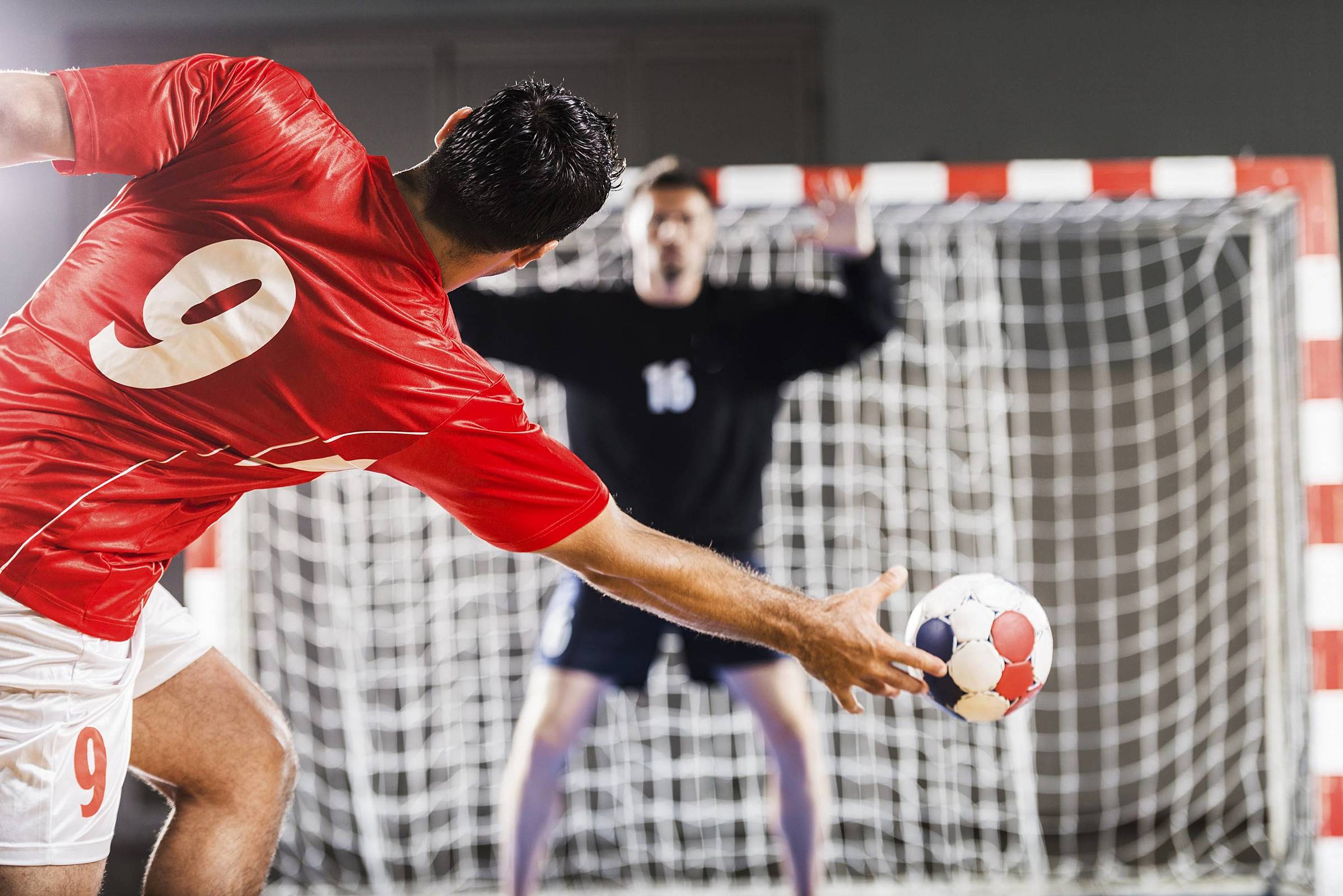 Jogador em frente ao goleiro durante uma partida de handebol