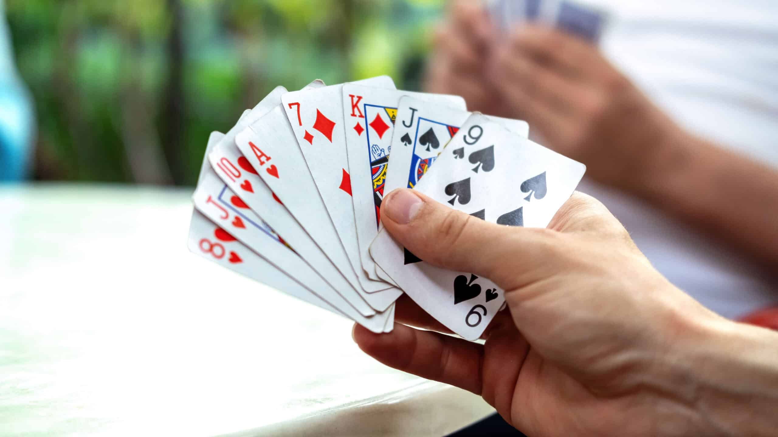 Mão de um homem segurando cartas durante uma partida de baralho.