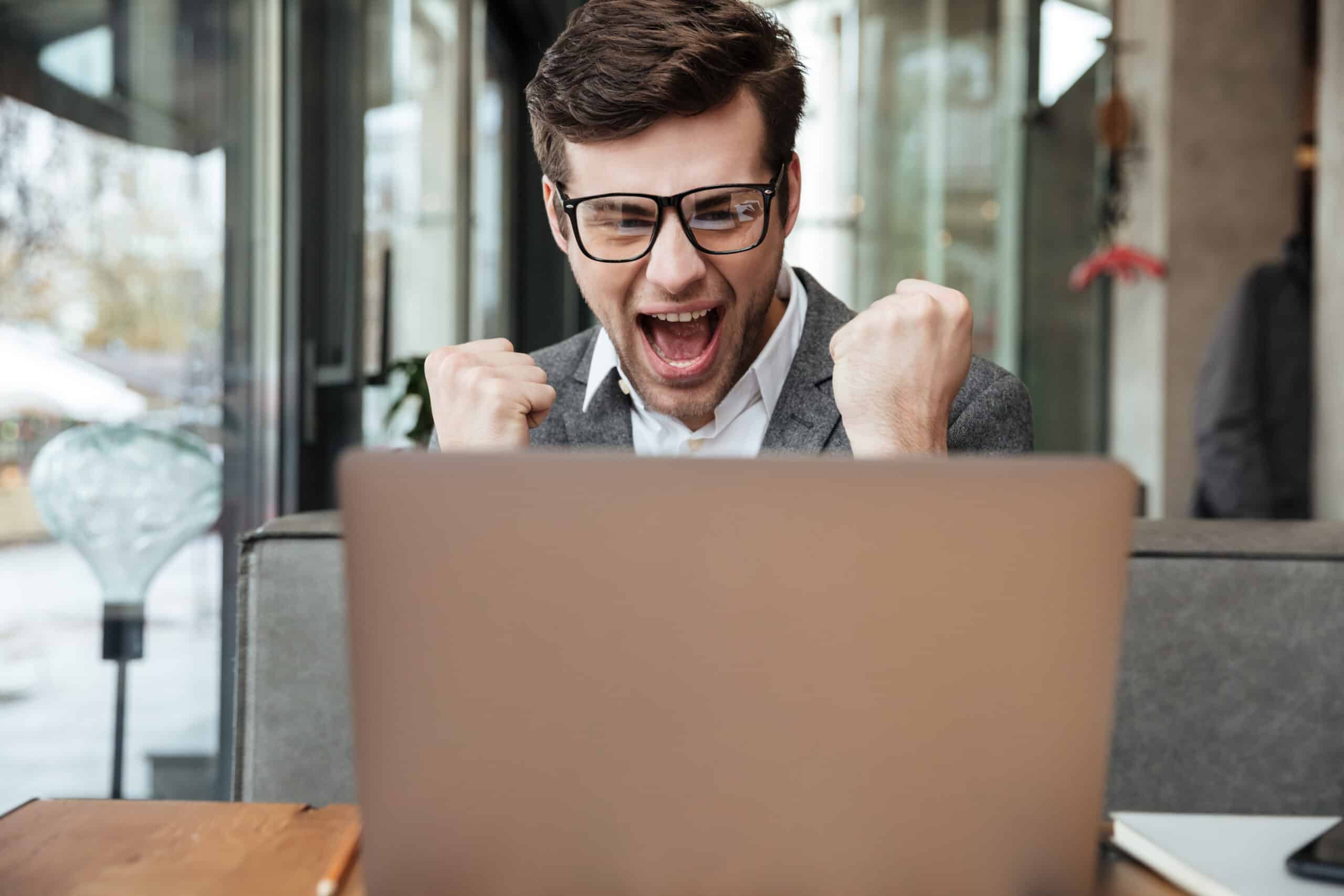 Homem comemorando em frente ao computador